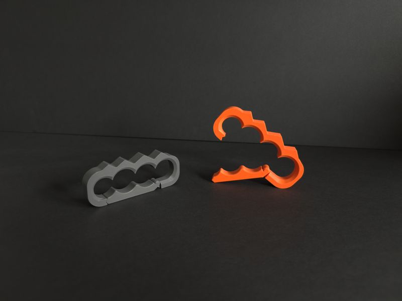 TactiClutch hinged carry clip standing open on a dark background, orange in front, grey behind