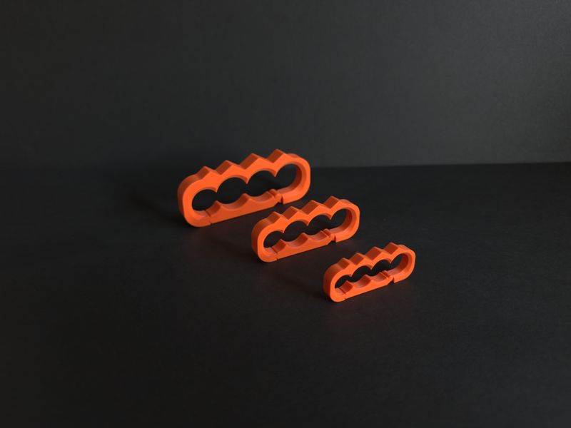 Three orange TactiClutch prototypes in three sizes lined up on a dark surface